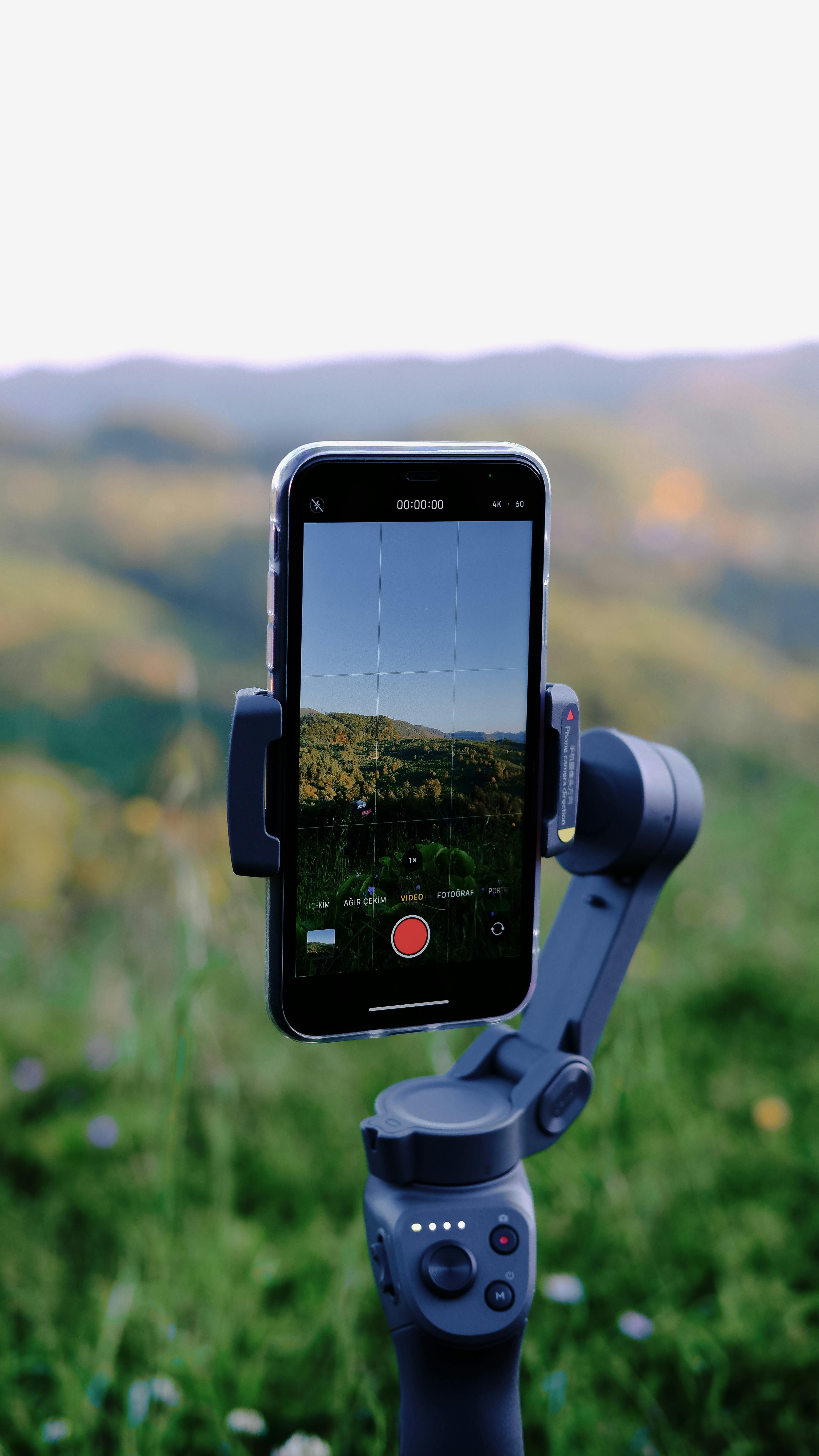 A smartphone mounted on a gimbal recording a video of a beautiful mountain landscape.